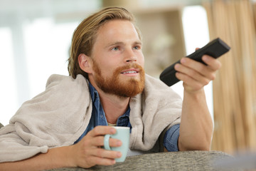 young man watching tv on a sofa at homehaving fun