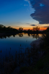 The sky with bright clouds lit by the sun after sunset over the lake.