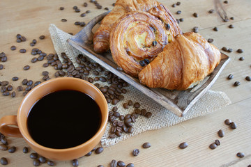 Sweet breakfast: black coffee, croissants and a roll with raisins