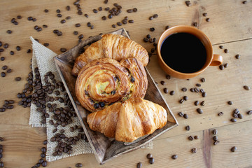 Sweet breakfast: black coffee, croissants and a roll with raisins
