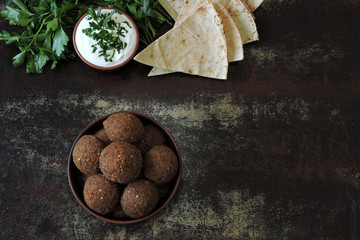 A bowl of falafel, white sauce, pita and parsley. Fresh falafel.