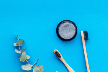 Eco materials concept with bamboo tooth brush and toothpaste with bamboo carbon on blue background top view