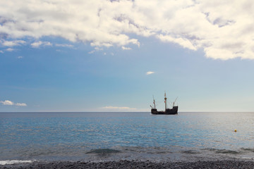 Silhouette of an old sailing vessel near the ocean shore.