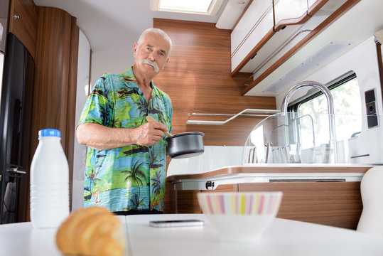 Senior Man Making Tea In Camper Van On Beach