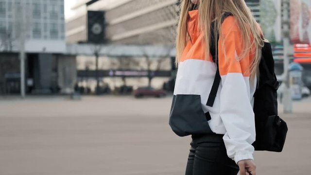 Beautiful young girl with roller skates in skate park. Young woman walk with rollerblades in hands on background of street. Close up view