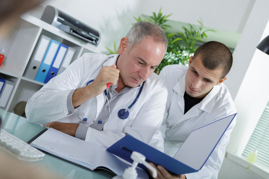 apprentice and doctor checking a patients folder
