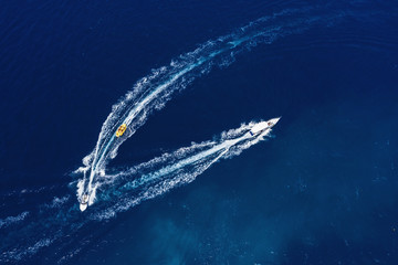 Yachts at the sea surface. Aerial view of luxury floating boat on transparent turquoise water at...