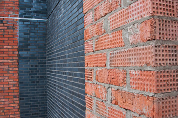 The wall is made of bricks. Brickwork in the construction of a new building. The use of a classic building material.