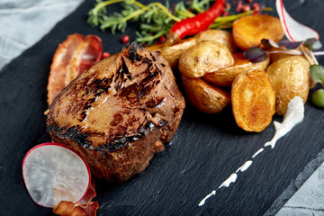 Beef steak served with baked potatoes and vegetables,black background, close-up. concept food.