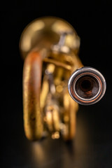 Old trumpet on a dark wooden table. Wind instrument in the old style.