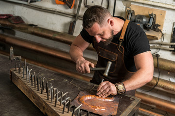 a blacksmith makes a piece of bronze
