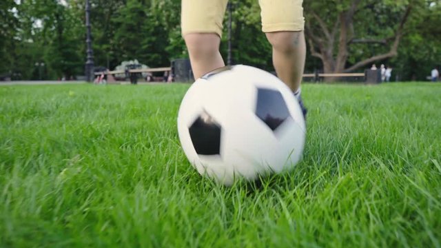 Boy playing soccer ball. Child with the ball runs through the green grass. Children's sport. Family holiday. The boy dreams of becoming a famous footballer. Training. Health. Happy childhood.