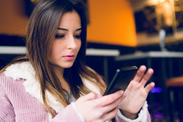 Young woman teenage using mobile phone to text message at the cafe browsing internet