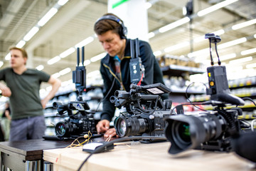 Videographer shooting a film or a television program in a studio with a professional camera,...