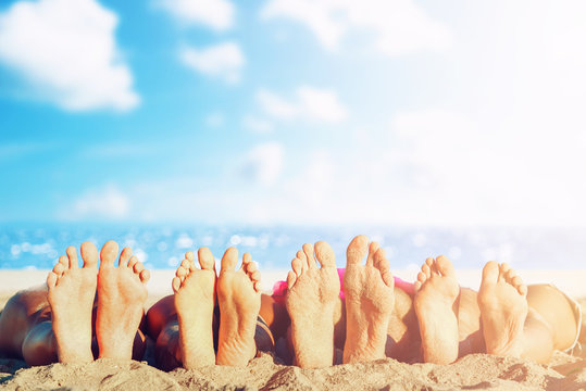 Group of friends having fun on the beach with their foots. Concept of summertime