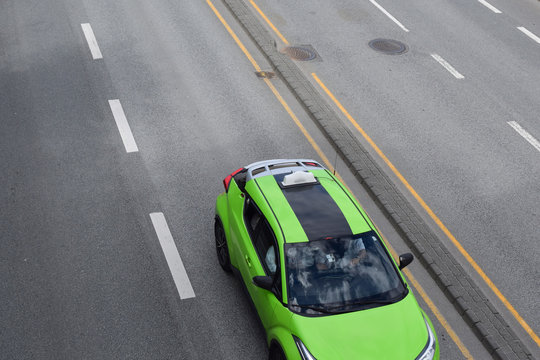 A passenger car of a green neon color is moving on the highway.
