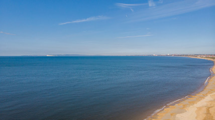An aerial view of a beautiful beach with crystal blue water under a majestic blue sky and some white clouds