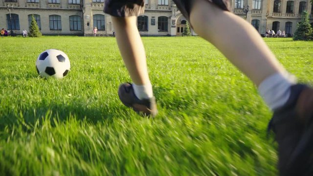 Boy playing soccer ball. Child with the ball runs through the green grass. Children's sport. Family holiday. The boy dreams of becoming a famous footballer. Training. Health. Happy childhood.