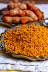 Fresh turmeric or curcuma root and dried powder, wildly used in Asia and India as spice, food ingredient and for medicinal purposes.