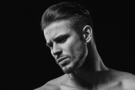 Muscular model young man with beard on dark background. Fashion portrait of brutal sexy strong muscle guy with modern trendy hairstyle. Model, fashion concept. Black and white.