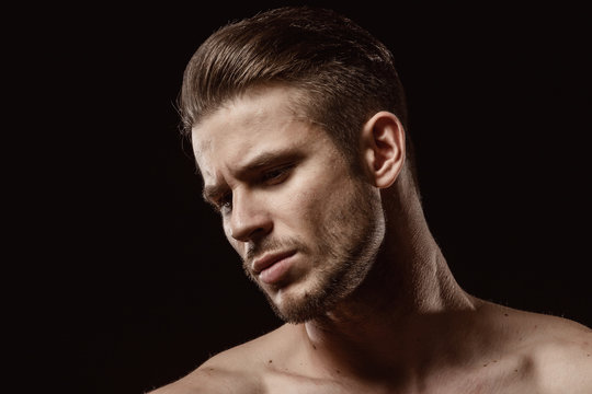 Muscular sexy model sports young man on a dark background. Portrait of sporty healthy strong brutal muscle guy with a modern trendy hairstyle.