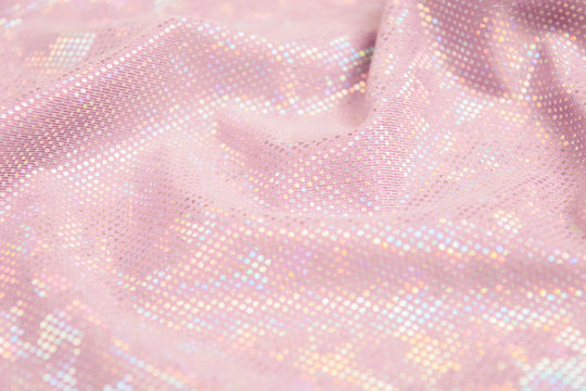 Pink shiny fabric textured background. Textile backdrop with waves. Selective focus