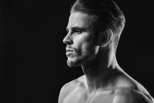 Muscular model young man with beard on dark background. Fashion portrait of brutal sexy strong muscle guy with modern trendy hairstyle. Model, fashion concept. Black and white.