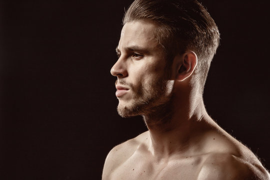 Muscular sexy model sports young man on a dark background. Portrait of sporty healthy strong brutal muscle guy with a modern trendy hairstyle.