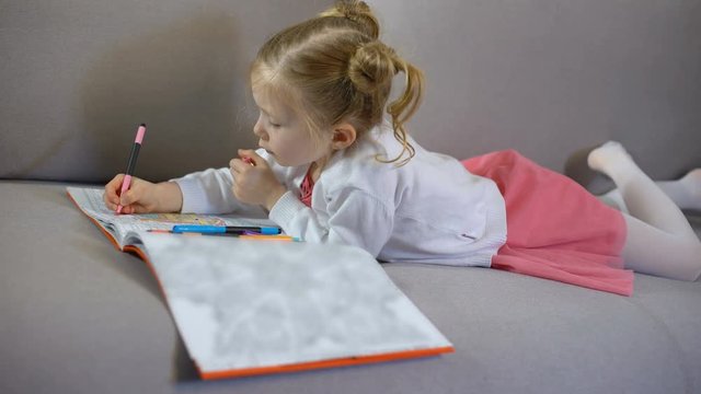 Cute little girl drawing with markers in coloring book, art therapy and hobby