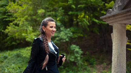 Portrait of smiling young girl with smartphone in hand on background of green park