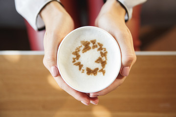 Glass with art cappuccino in female hands