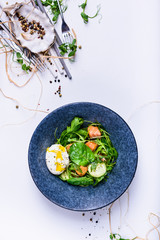 Green spring salad with spinach, salmon and egg in a bowl. Healthy eating concept.