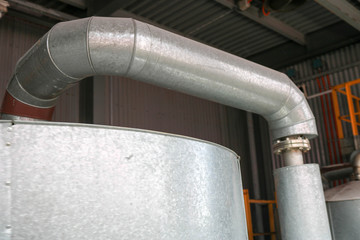 Large iron heat exchanger, tank, reactor, distillation column in thermal insulation of fiberglass and mineral wool of galvanized steel in the industrial refinery petrochemical plant shop