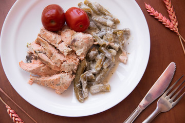 Baked red fish with green beans. . Fish with beans on a plate. Red Pickled Tomatoes
