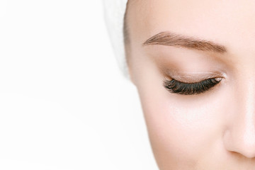 Eyelash extension procedure. Beautiful woman with long eyelashes and perfect glow clean skin. Girl in beauty salon getting facial treatment. Perfect trendy eyebrows.