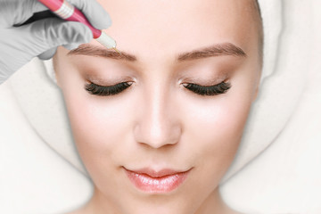 Beautiful young girl with long eyelashes tweezing her eyebrows in a beauty salon. Woman doing...