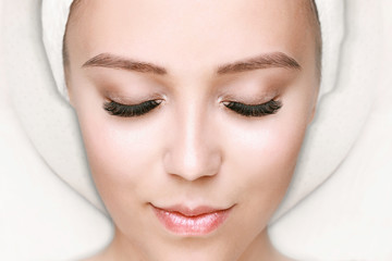 Fototapeta na wymiar Eyelash extension procedure. Beautiful woman with long eyelashes and perfect glow clean skin. Girl in beauty salon getting facial treatment. Perfect trendy eyebrows.