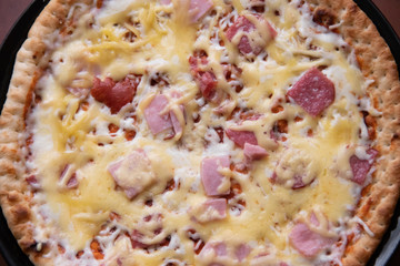 Round finished pizza on a plate. Delicious food. pizza on a black plate on the table