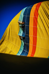 Detail of multicolored fabric of a hot air balloon deflating, vertical image.