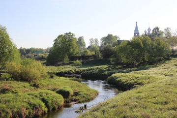 Fototapeta na wymiar Summer village landscape with river, green trees, blue sky, old church