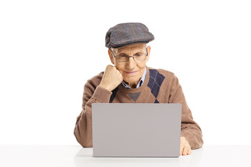 Elderly man sitting and reading on a laptop computer