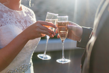 Dating or wedding concept - couple drinking white wine or champagne outdoors. A young couple clink glasses with an alcoholic drink. Sun glare in the glasses.