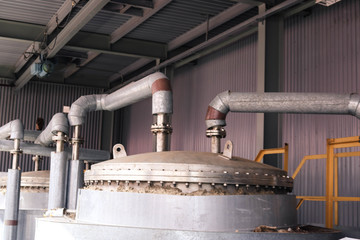 Stainless steel metal lid with bolts and studs, top of the heat exchanger of a chemical rectification column with a pipe with flanges at an industrial refinery petrochemical plant