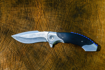 Folding knife on the rustic wooden background