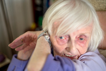 Elderly lady with macular degeneration listens to her speaking wrist watch,England,U.K.