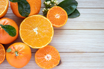 Fresh oranges fruits  and slices with green leaves on wood background. Home gardening.