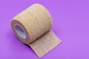 Elastic Self-Adhering Compression Bandage (Cohesive Bandage) on purple background.