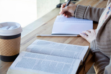 hand writing notes while she studies her bible 