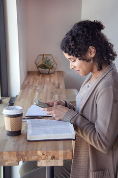woman smiles as she looks at her phone while doing a bible study