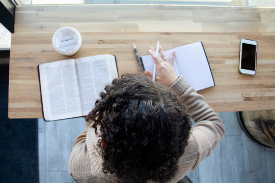 top view of black woman making notes while studying her bible